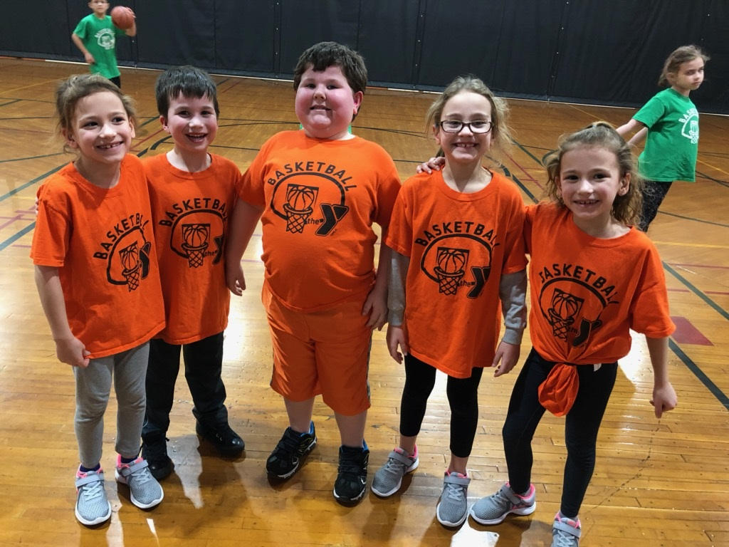 ISD Elementary YMCA basketball team posing together for a picture on the basketball court. .